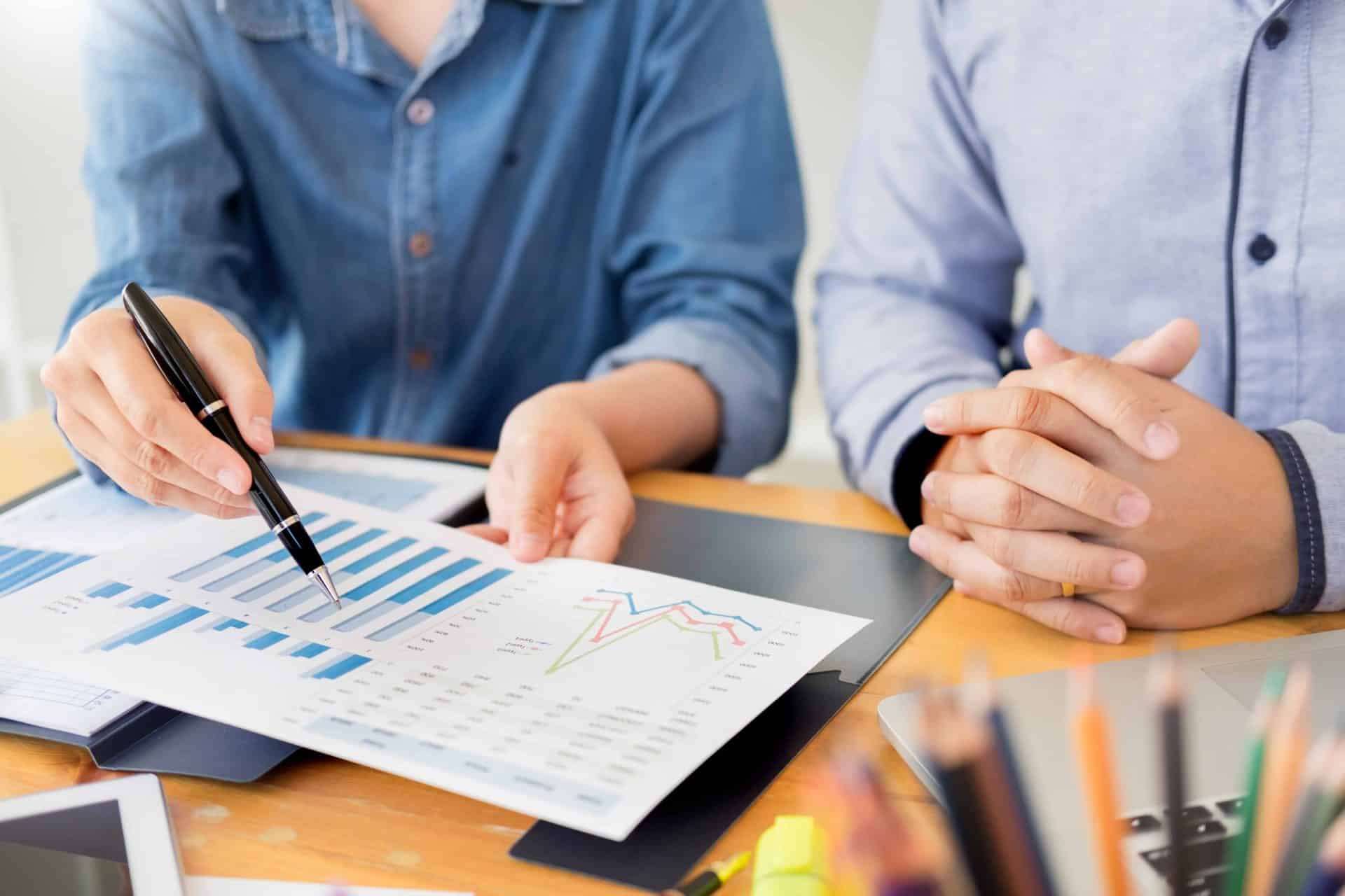 business meeting with close up of financial reporting and professional pointing at report